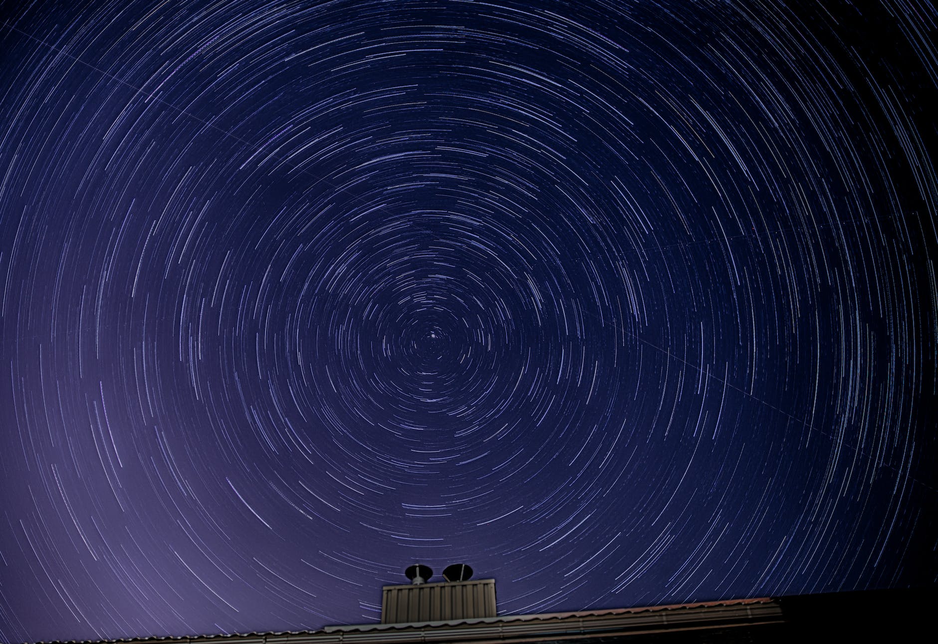 stars in blue night sky over roof of building