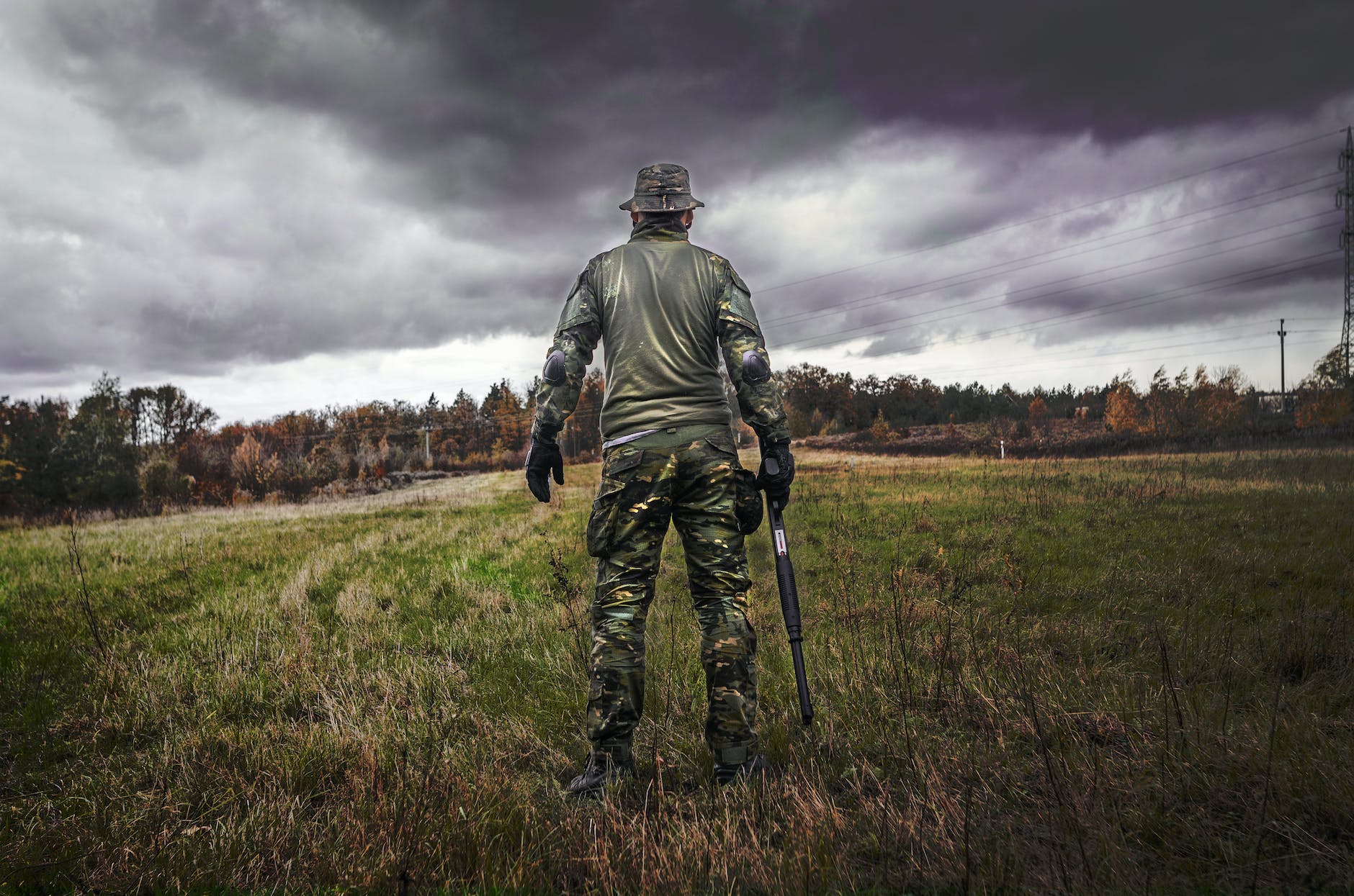 man in camouflage suit holding shotgun