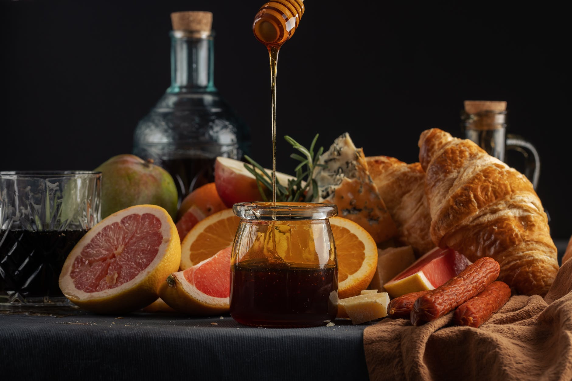 sliced orange fruit beside clear glass jar with honey