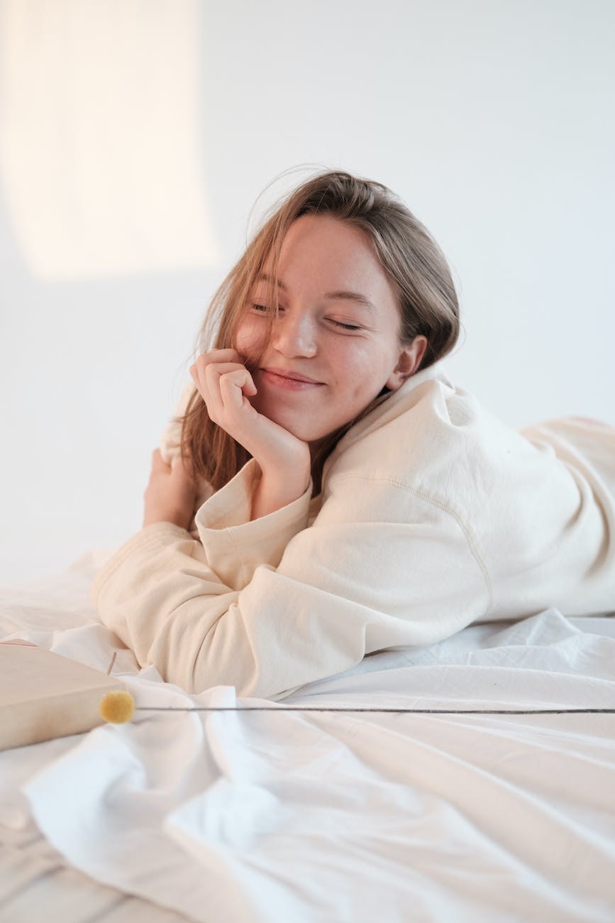optimistic female resting on bed with closed eyes
