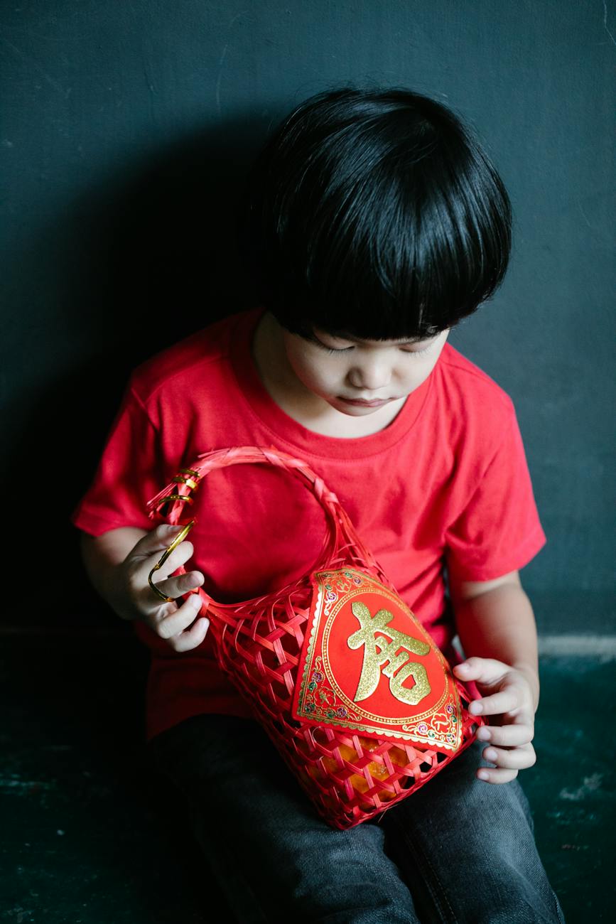 adorable ethnic little boy holding gift basket near dark wall