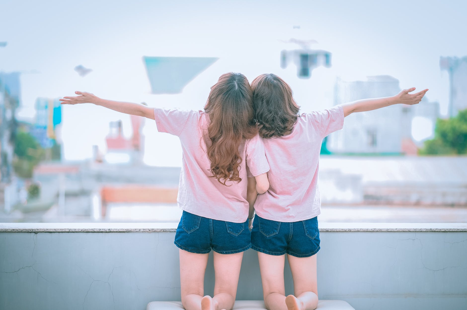 two girls spreading arms together while kneeling