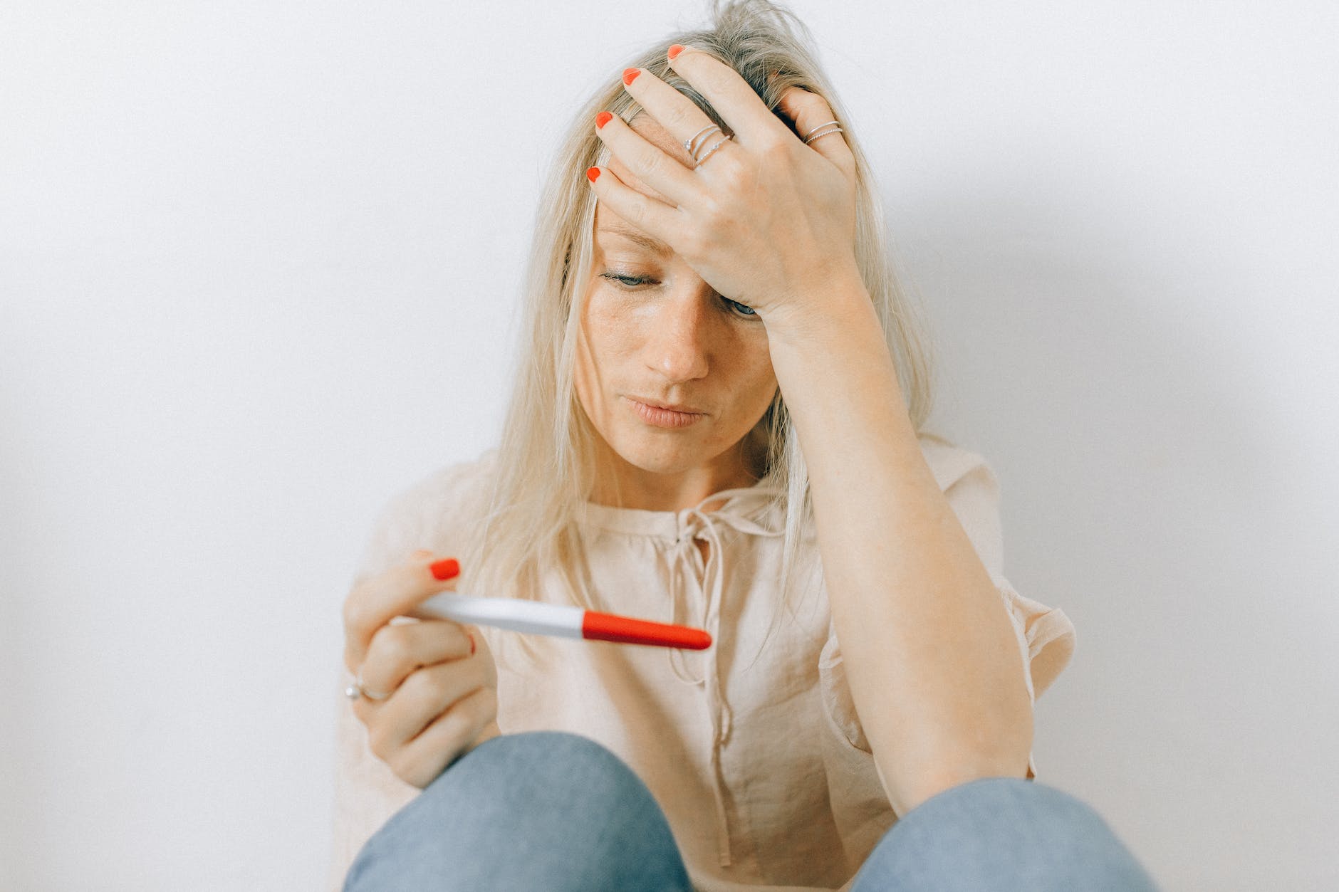 a woman looking depressed at a pregnancy test