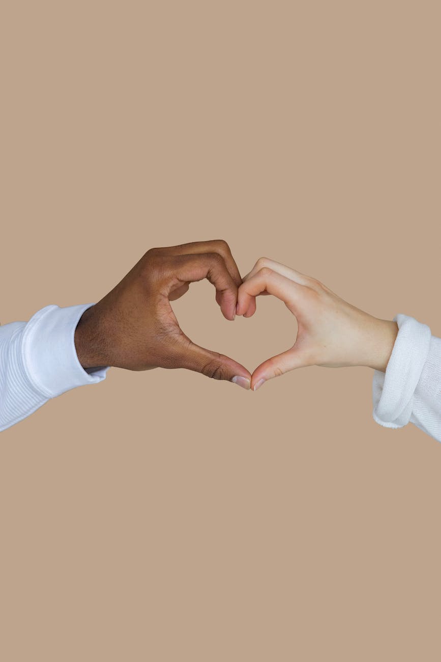 close up photo of heart shaped hands by two people