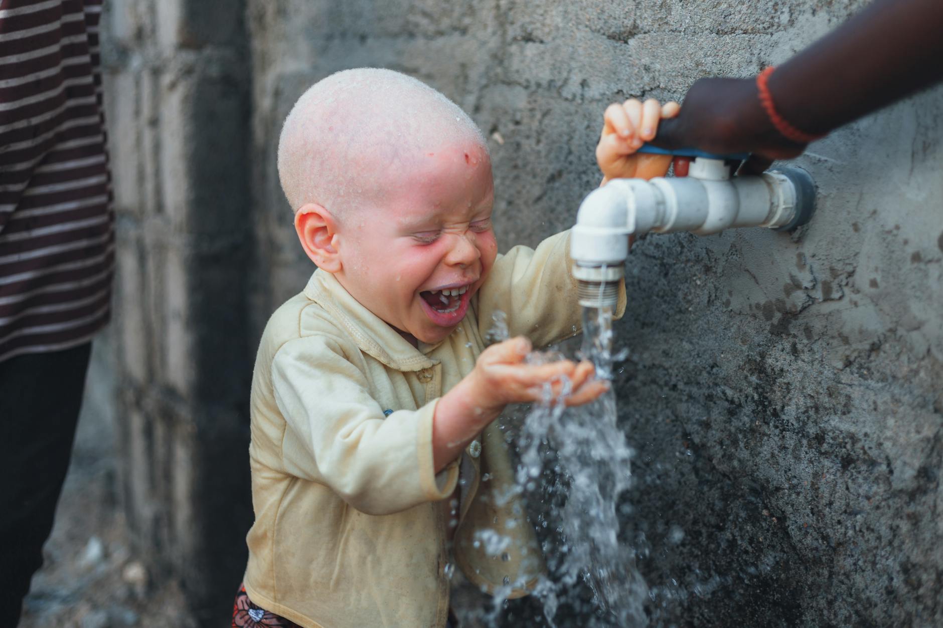smiling boy near faucet with water
