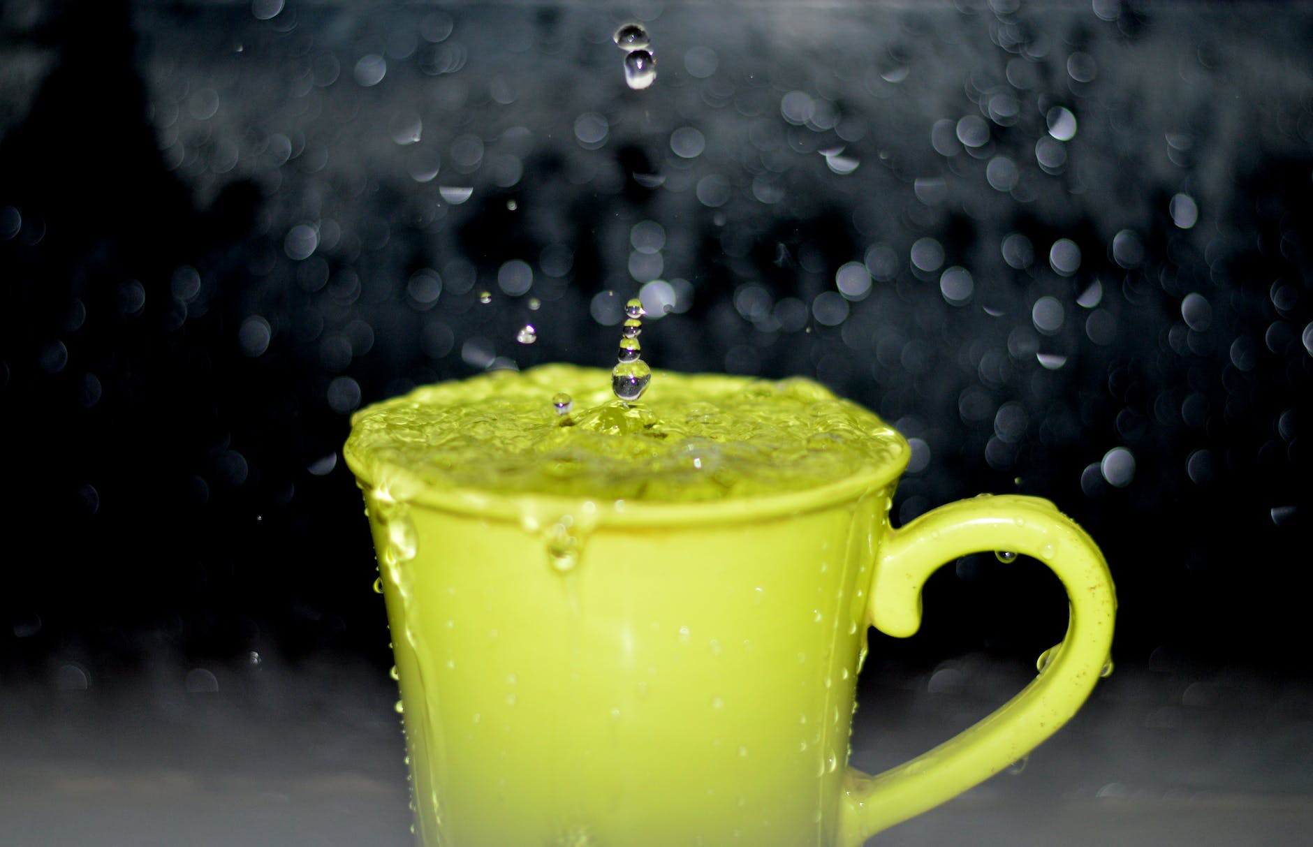 yellow ceramic mug with water droplets in time lapse photography