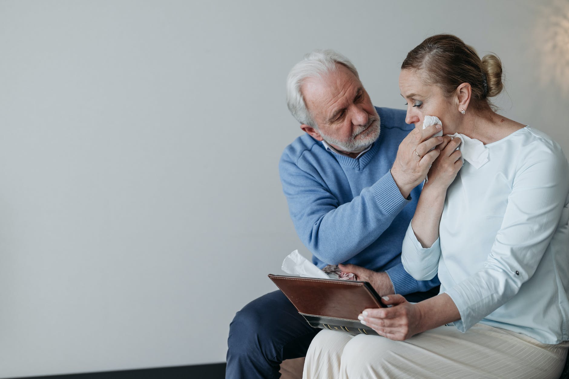 an elderly man wiping his wife tears