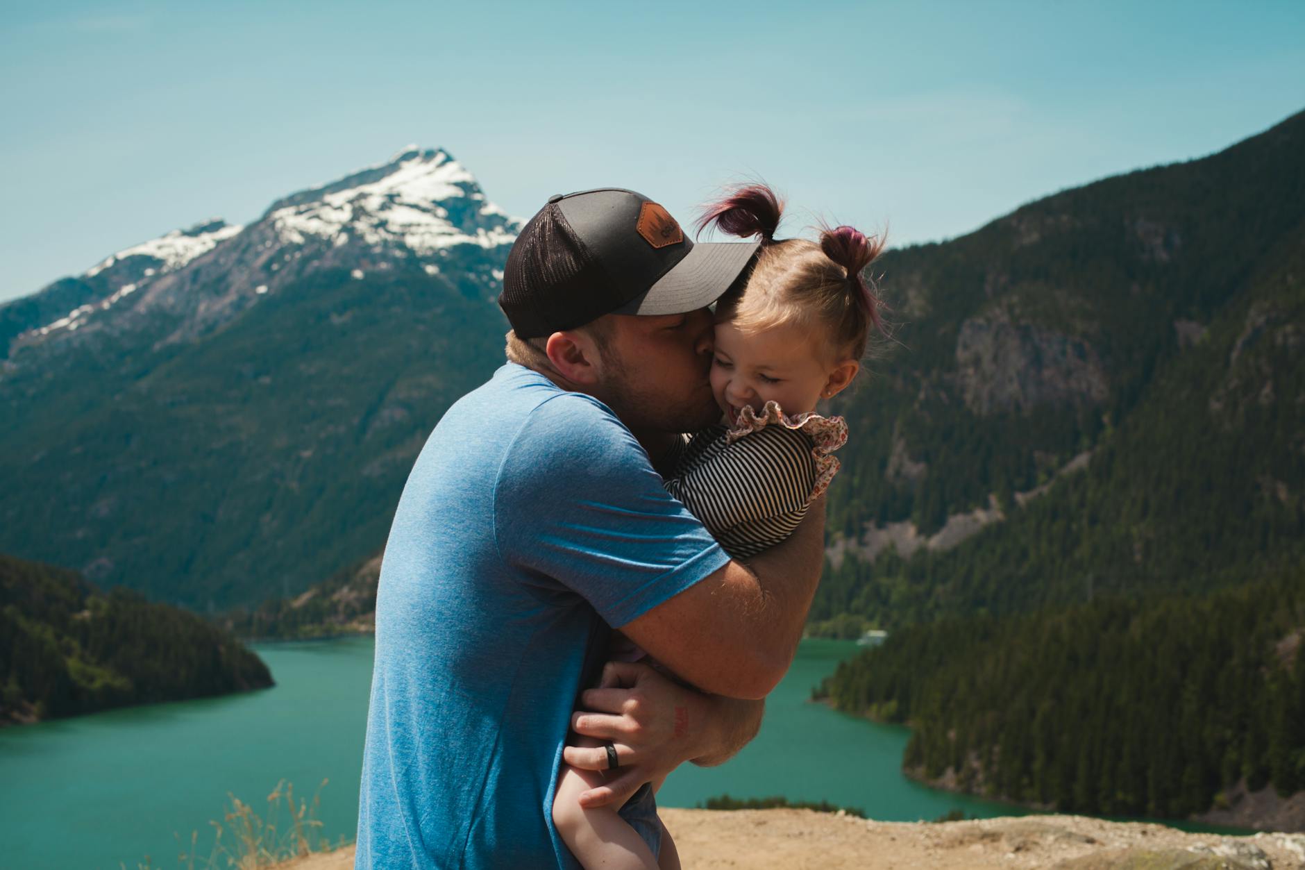 father hugging and kissing his daughter in a mountain landscape
