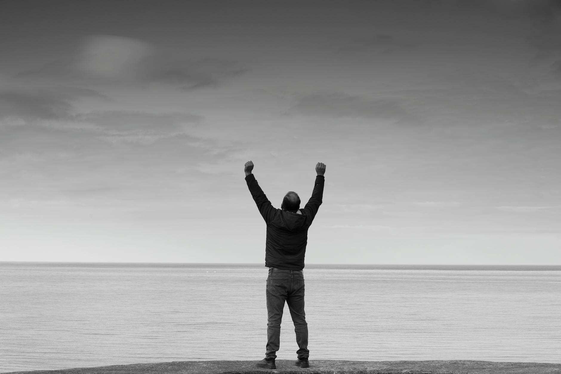 silhouette of a person celebrating by the sea