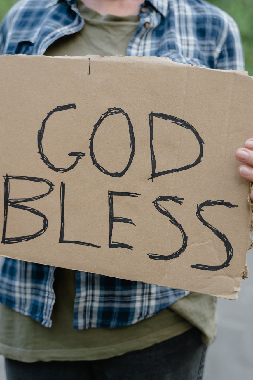 a man holding a god bless sign written on a cardboard