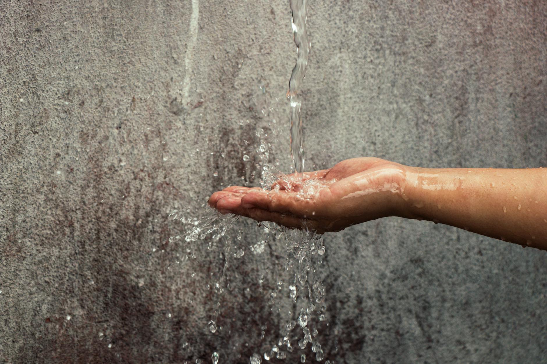 photo of hand catching flowing water