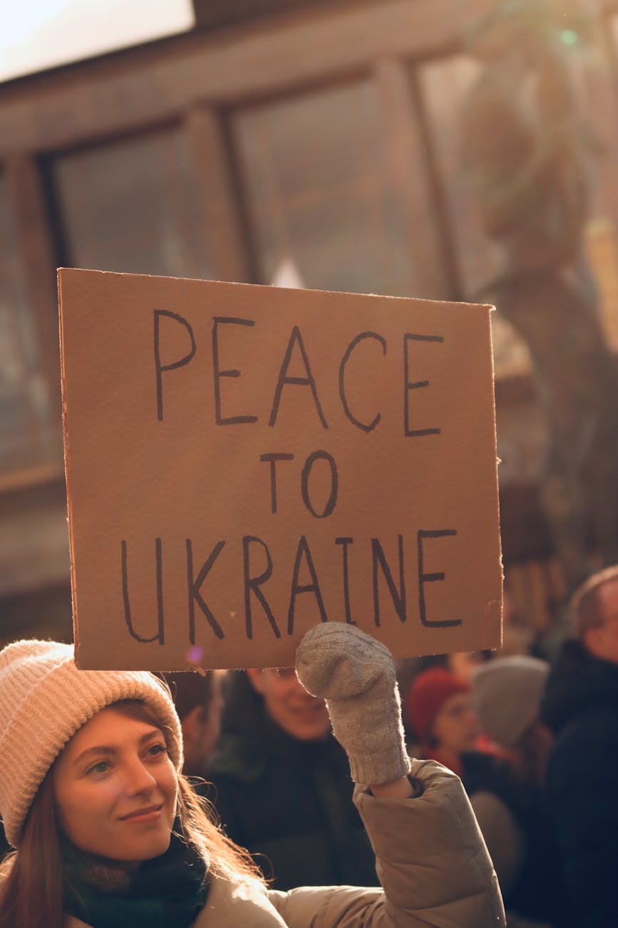 a woman wearing winter clothing holding a placard with message