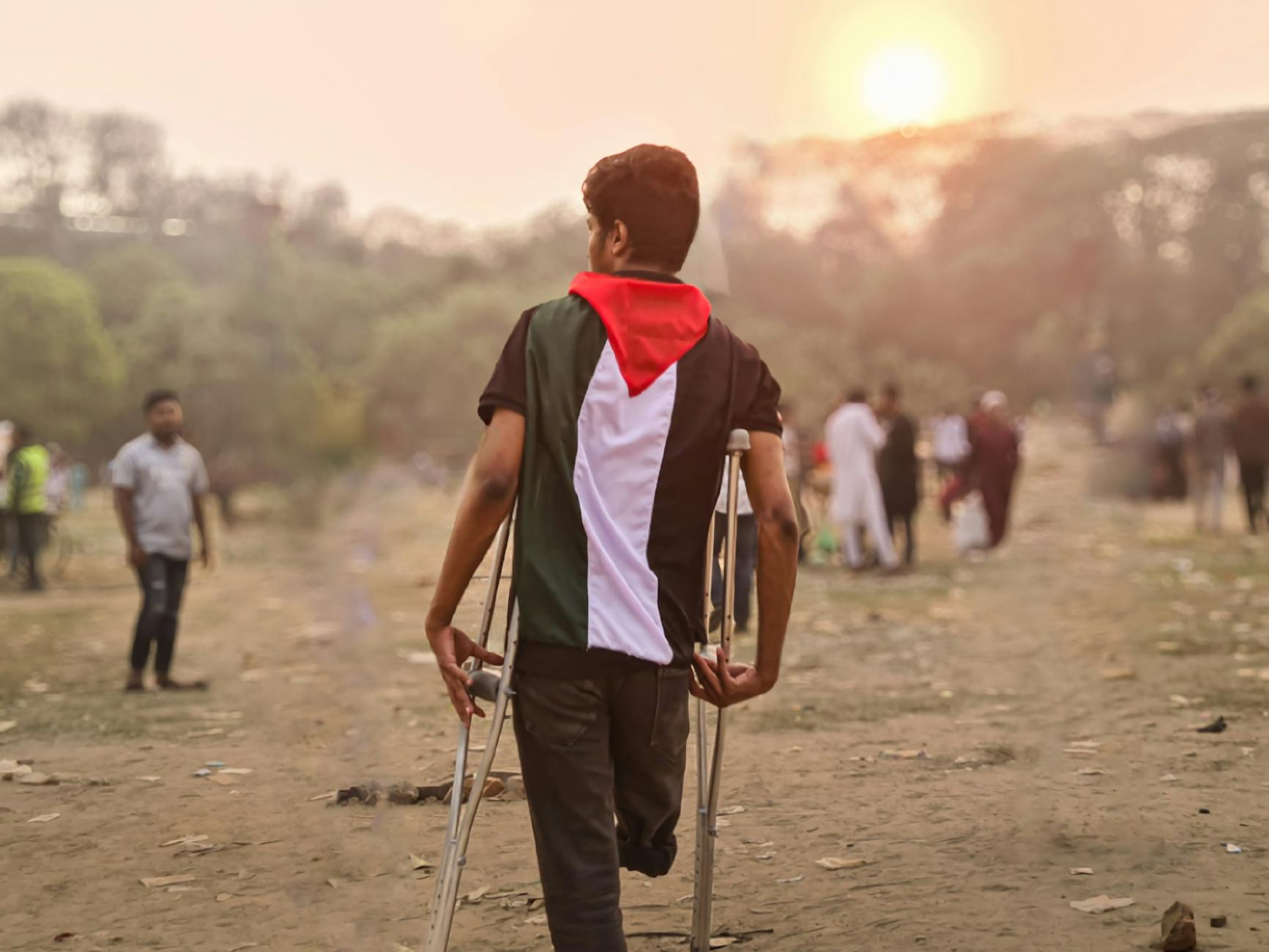 young man with palestinian flag and crutches outdoors