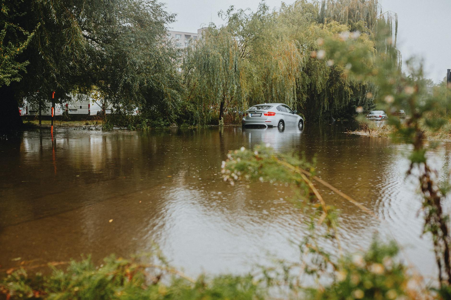 car navigating flooded street after heavy rain