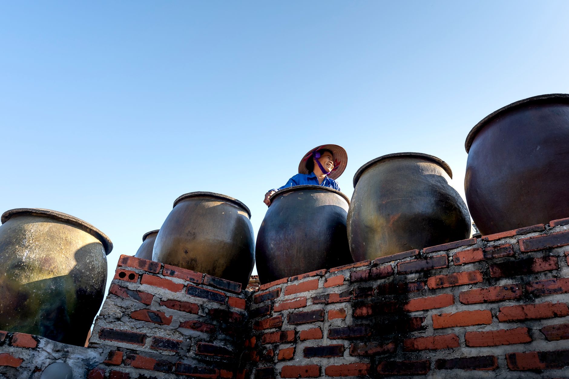 smiling woman in conical hat near jugs